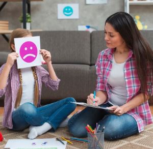 A BOY HOLDING AN UNHAPPY EMOJI CHART AND A LADY LOOKING AT THAT