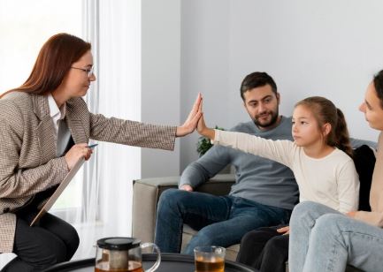 A child sitting with her parents is giving high five to a woman with a clipboard
