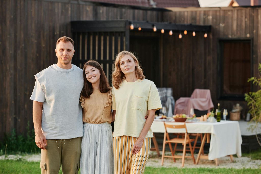 A man and lady standing with a teen girl and smiling