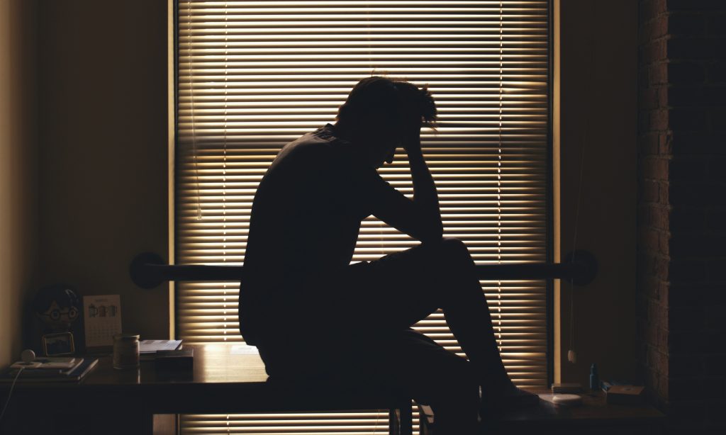 person sitting on a table with stress holding his forehead