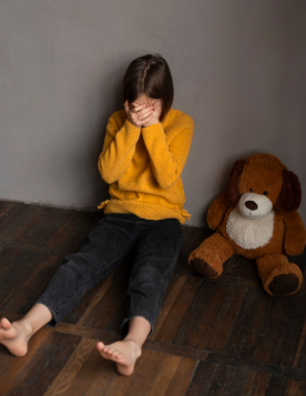 Child feeling sad sitting on floor by closing his face with his hands