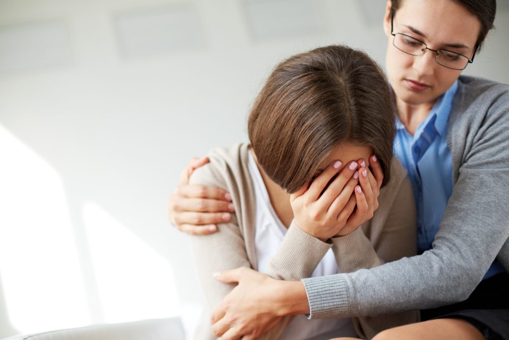 Image of compassionate psychiatrist comforting her crying patient